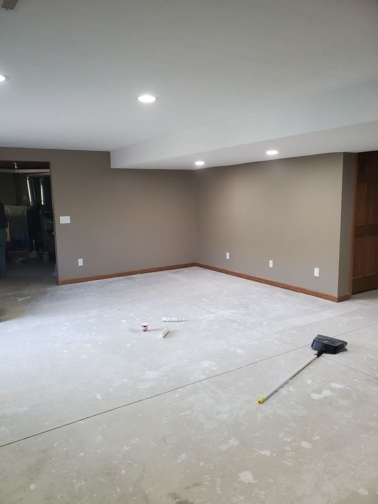 An empty basement with a measuring tape on the floor.