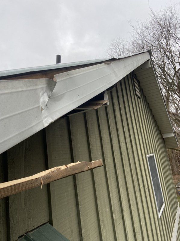 A house with a roof that has been damaged by a tree.