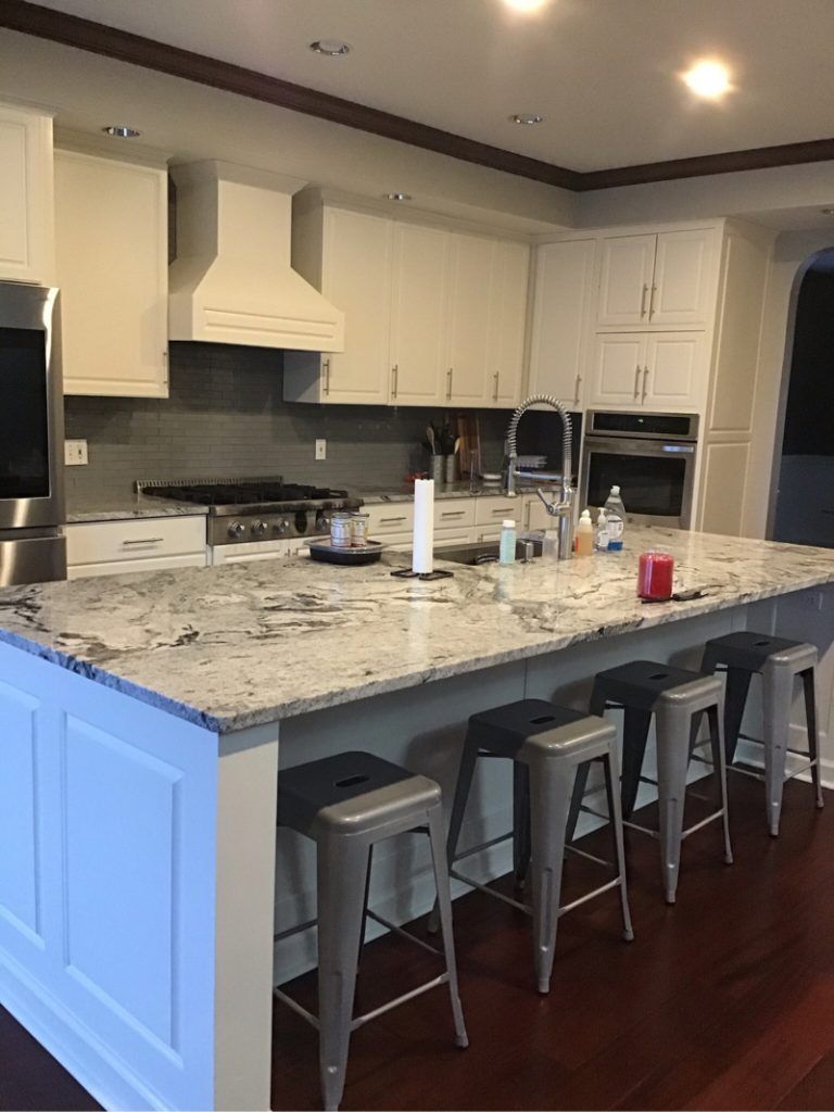 A kitchen with a large island and stools.
