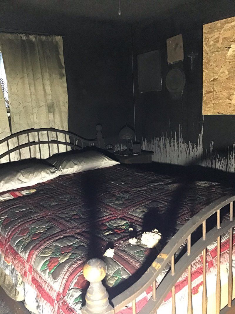 A fire damaged bedroom with a bed and a window.