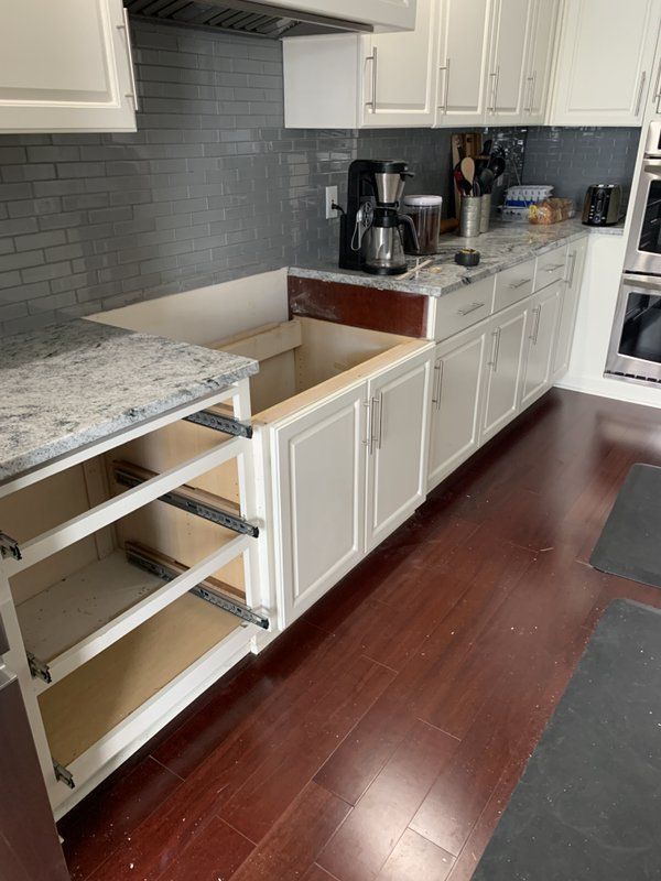 A kitchen with white cabinets , granite counter tops , and hardwood floors.