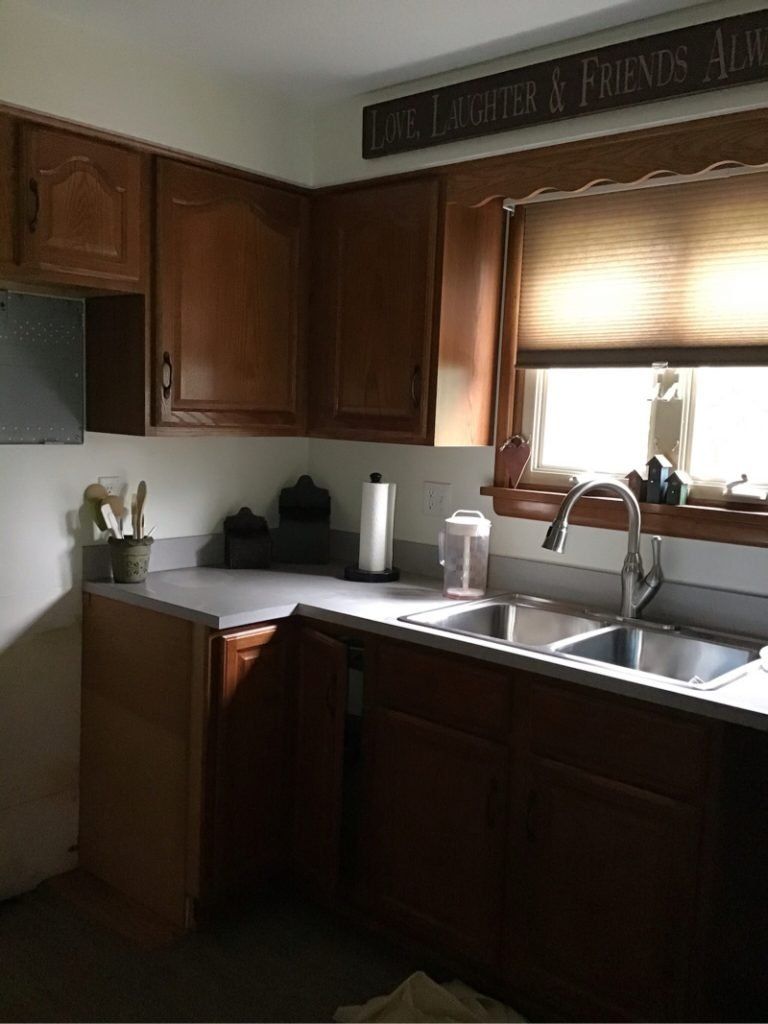 A kitchen with two sinks and a sign that says life laughter and friends above the sink.