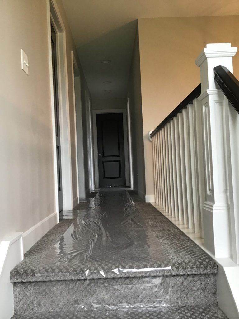 A hallway with stairs and a railing covered in plastic.