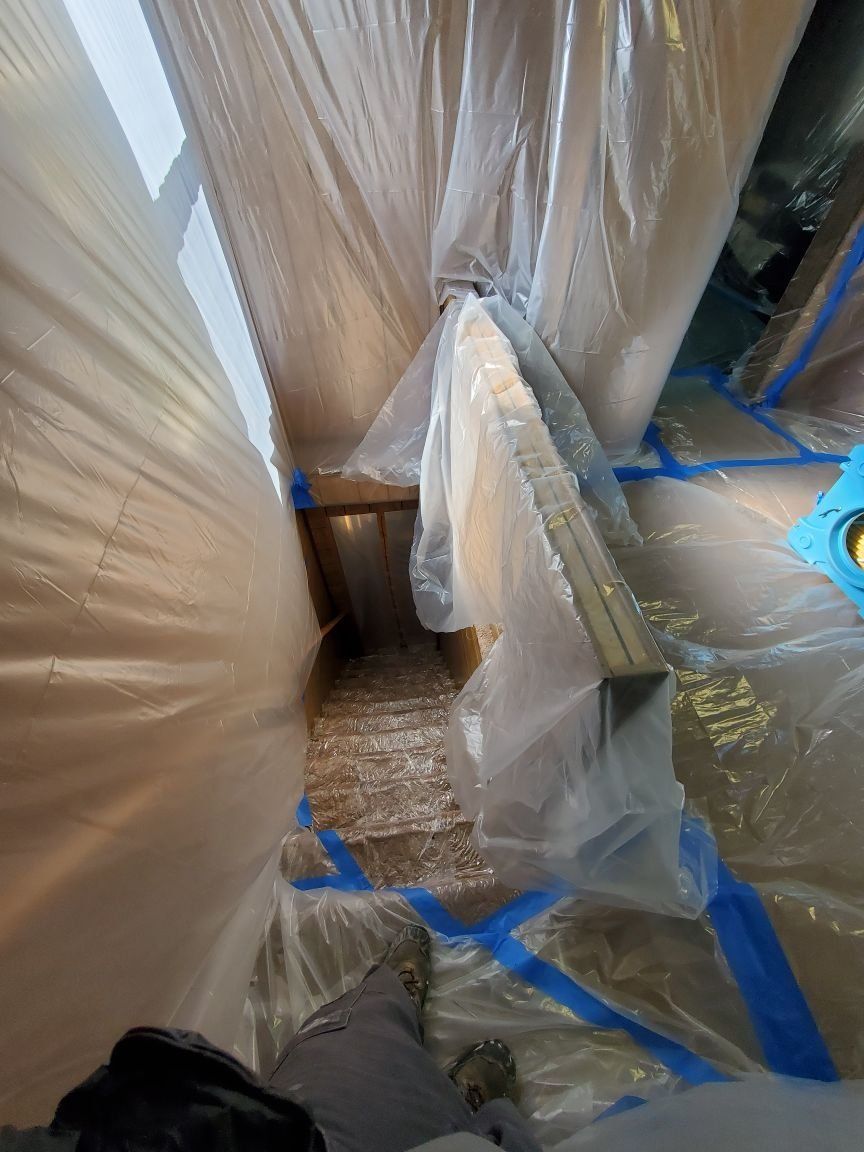 A room is covered in plastic and blue tape.
