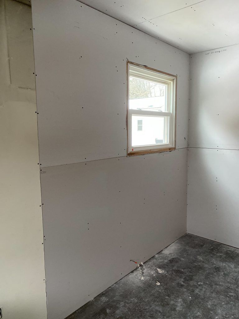 A room with a window and a white wall.