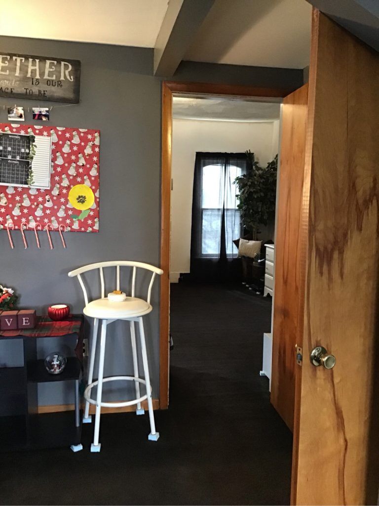 A white bar stool is sitting in a hallway next to a door.