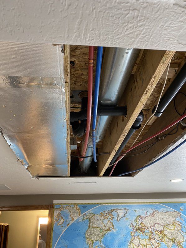 There is a hole in the ceiling with pipes coming out of it caused by water damage.