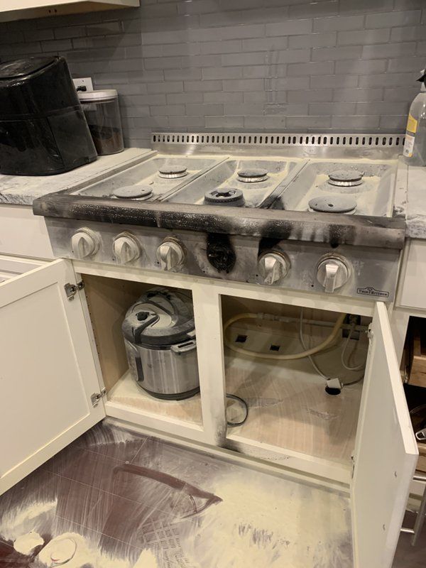 A kitchen with a stove top oven that has been damaged by a fire.