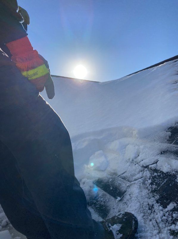 A person is standing on a snowy hill with the sun shining through the snow.