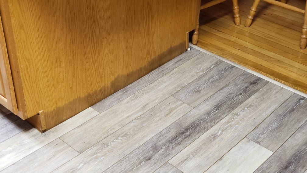 A close up of a wooden floor in a kitchen.