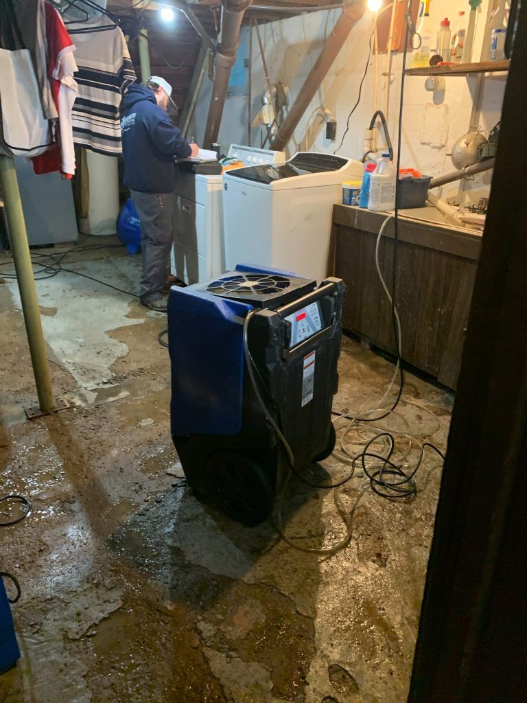 A man is working on a washing machine in a basement.