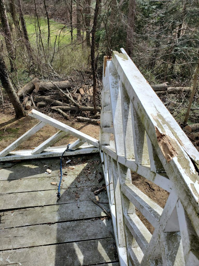 A broken wooden bridge in the middle of a forest.