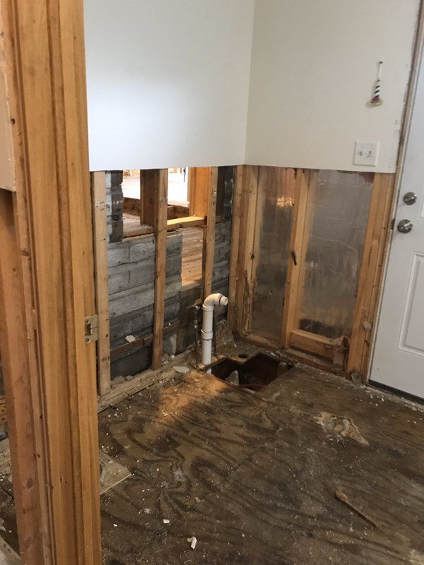 A water damaged room with a hole in the wall and a pipe in the floor.