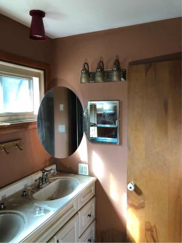A bathroom with two sinks , a mirror, and a window.