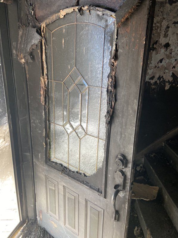 A fire damaged door with a stained glass window in a room.