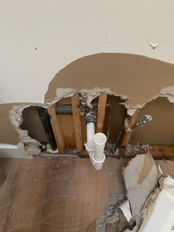 A hole in a damaged wall with a pipe coming out of it.