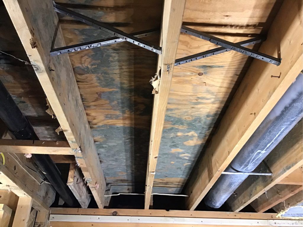 A damaged wooden ceiling with pipes coming out of it.
