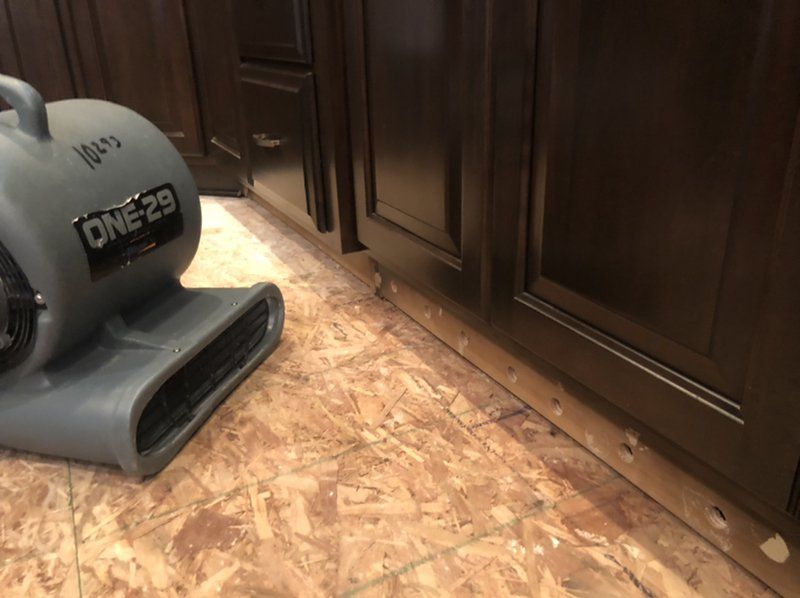An industrial dryer is sitting on the floor in a kitchen next to a cabinet.