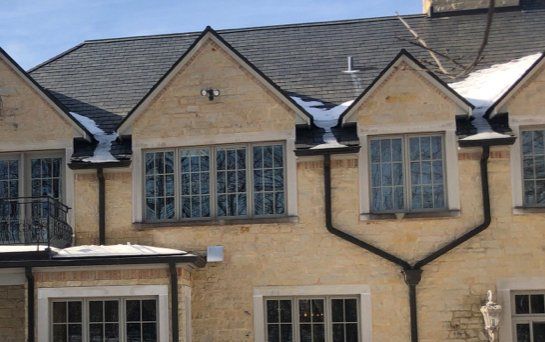 A brick house with a lot of windows and gutters on it