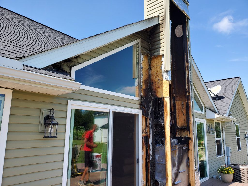 Exterior picture of the home with the chimney opened up, exposing the burnt elements of it.