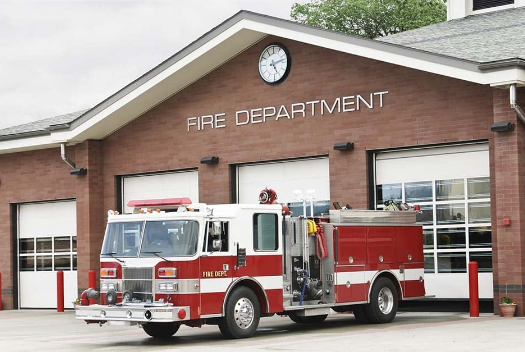 A fire truck is parked in front of a fire department building.