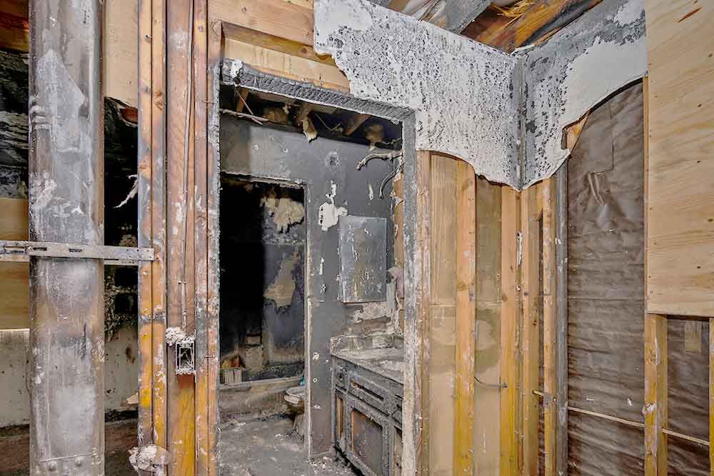 A damaged room with a lot of wooden walls and a door.