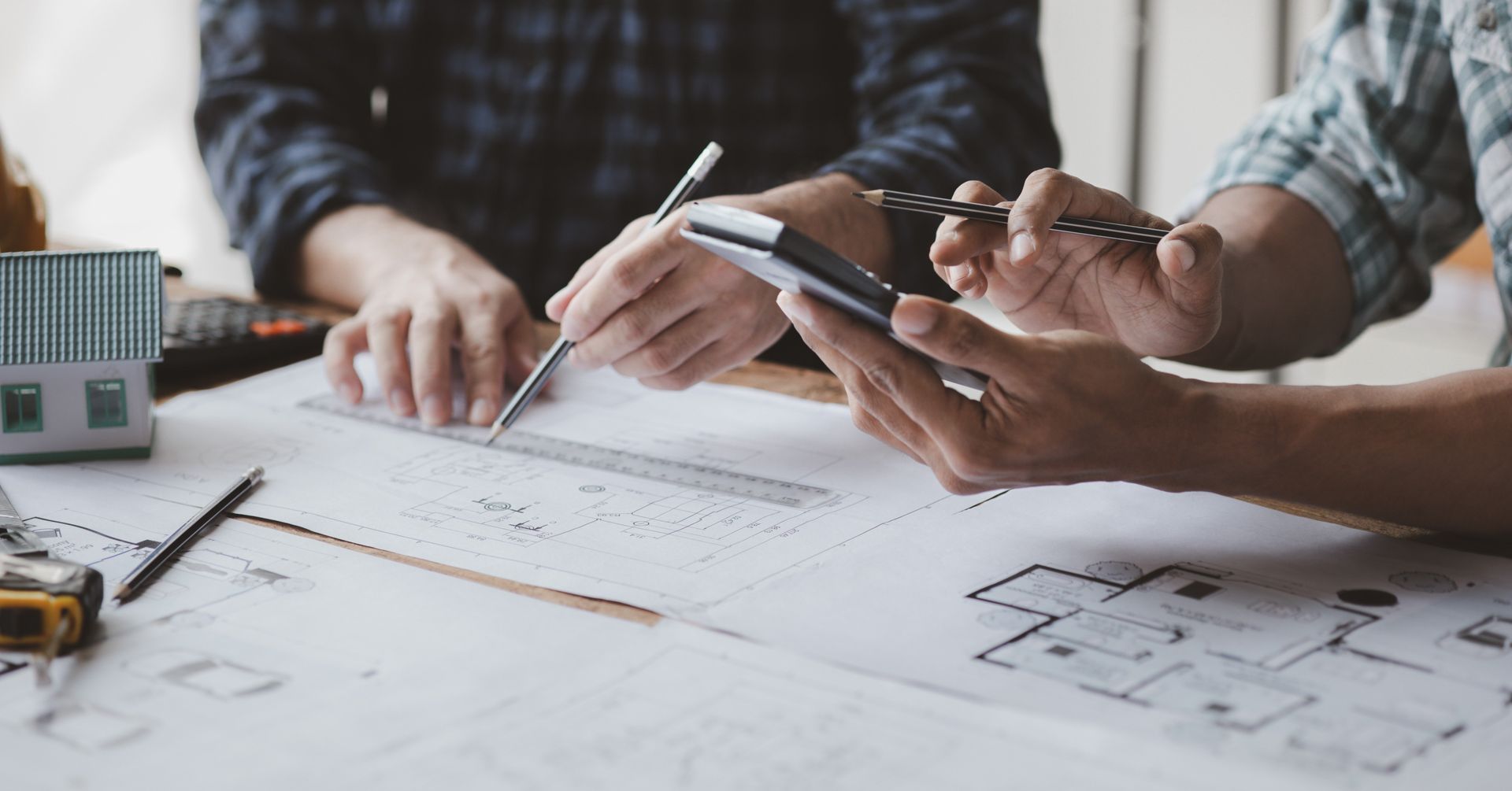 A group of people are sitting at a table looking at a blueprint.