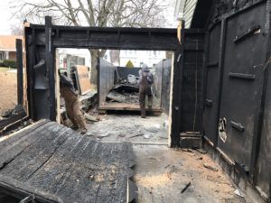 Two men working to repair a structure with fire damage.