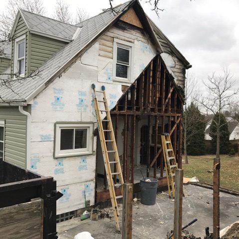 A house that has been damaged by a fire and is being remodeled with two ladders on the side.