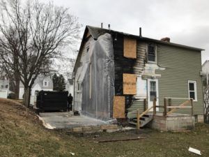 A house that has been damaged by a fire and is covered in plastic.