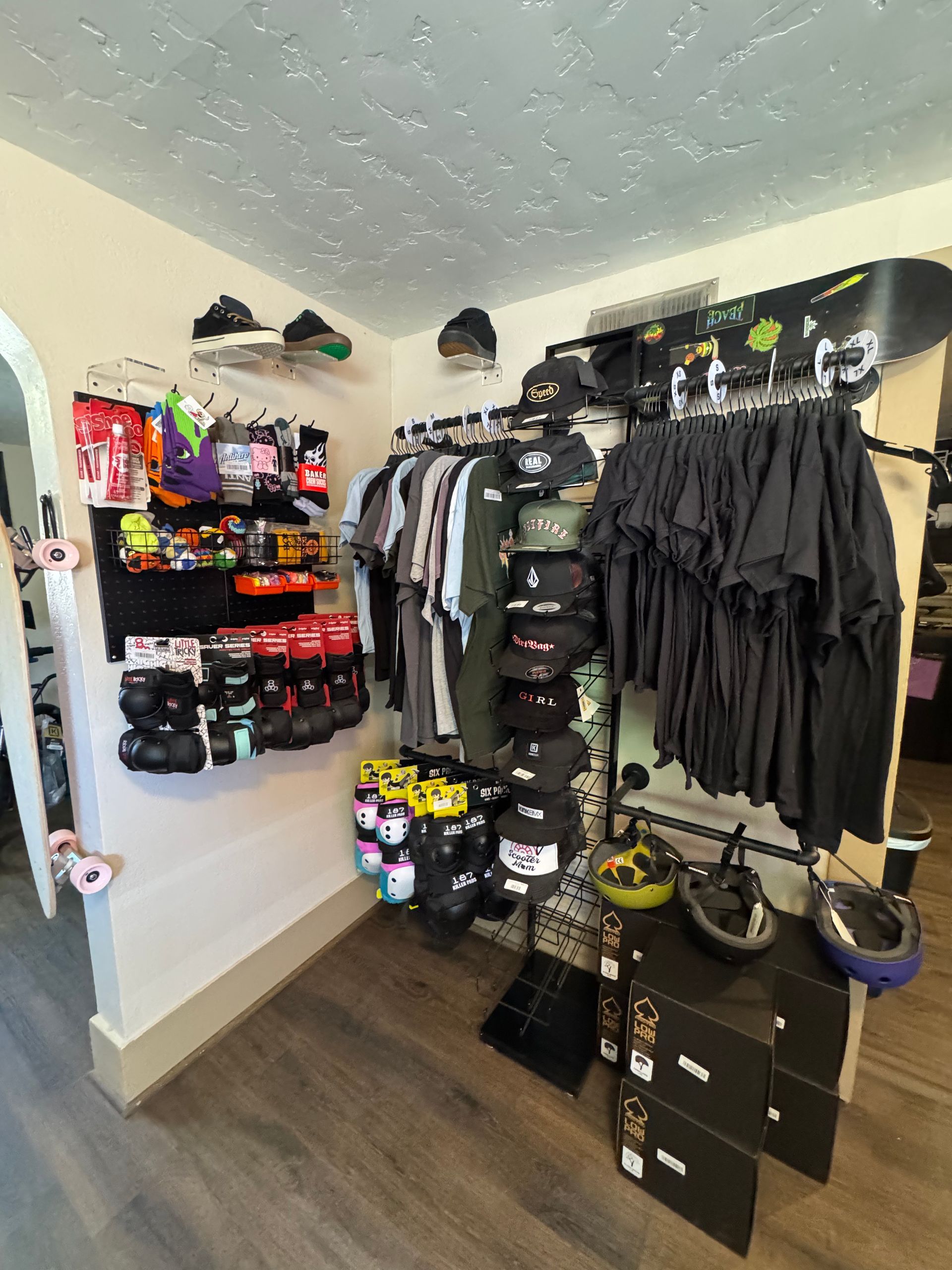 A room with a lot of clothes hanging on the wall and a snowboard on the wall.