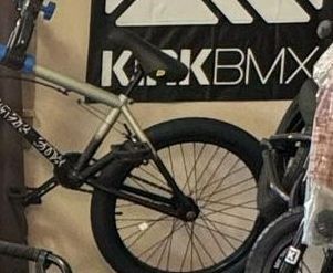 A bmx bike is hanging on a wall next to a sign.