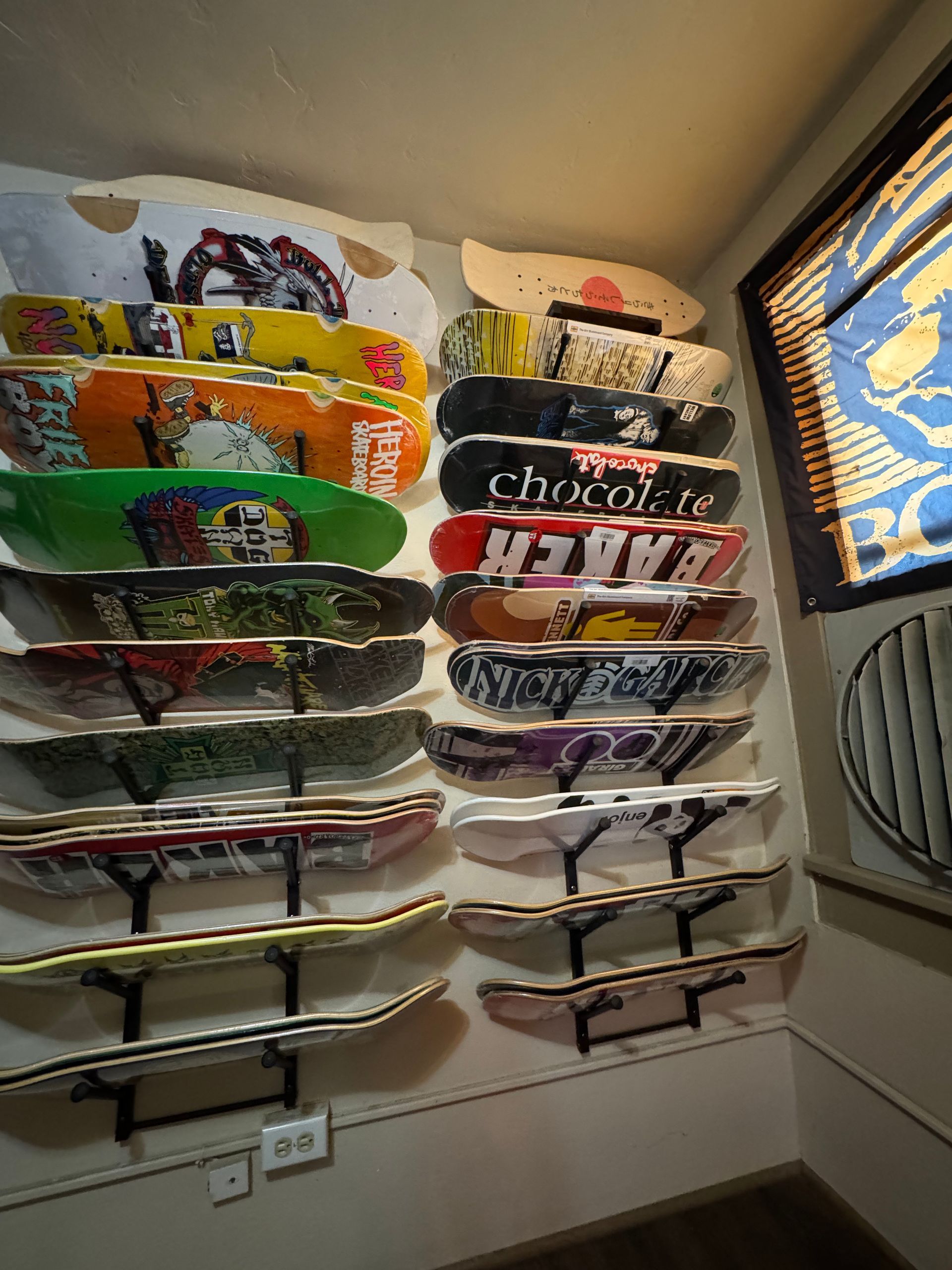 A bunch of skateboards are stacked on top of each other on a wall.