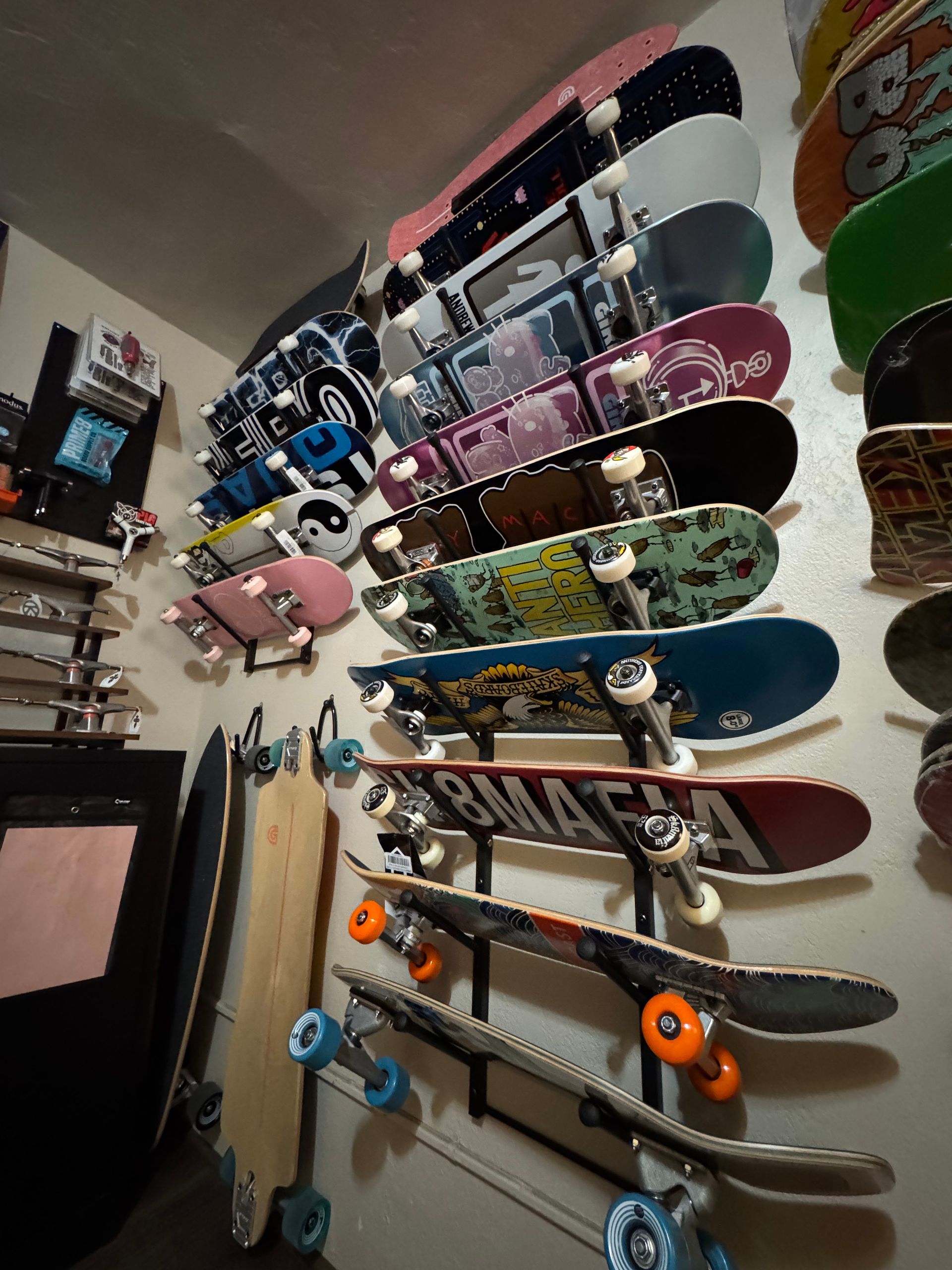 A bunch of skateboards are hanging on a wall in a room