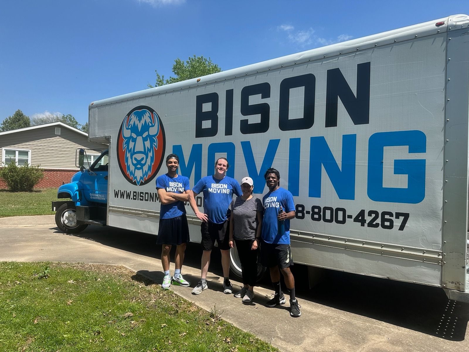 A group of people standing in front of a bison truck - Tulsa, OK - Bison Moving