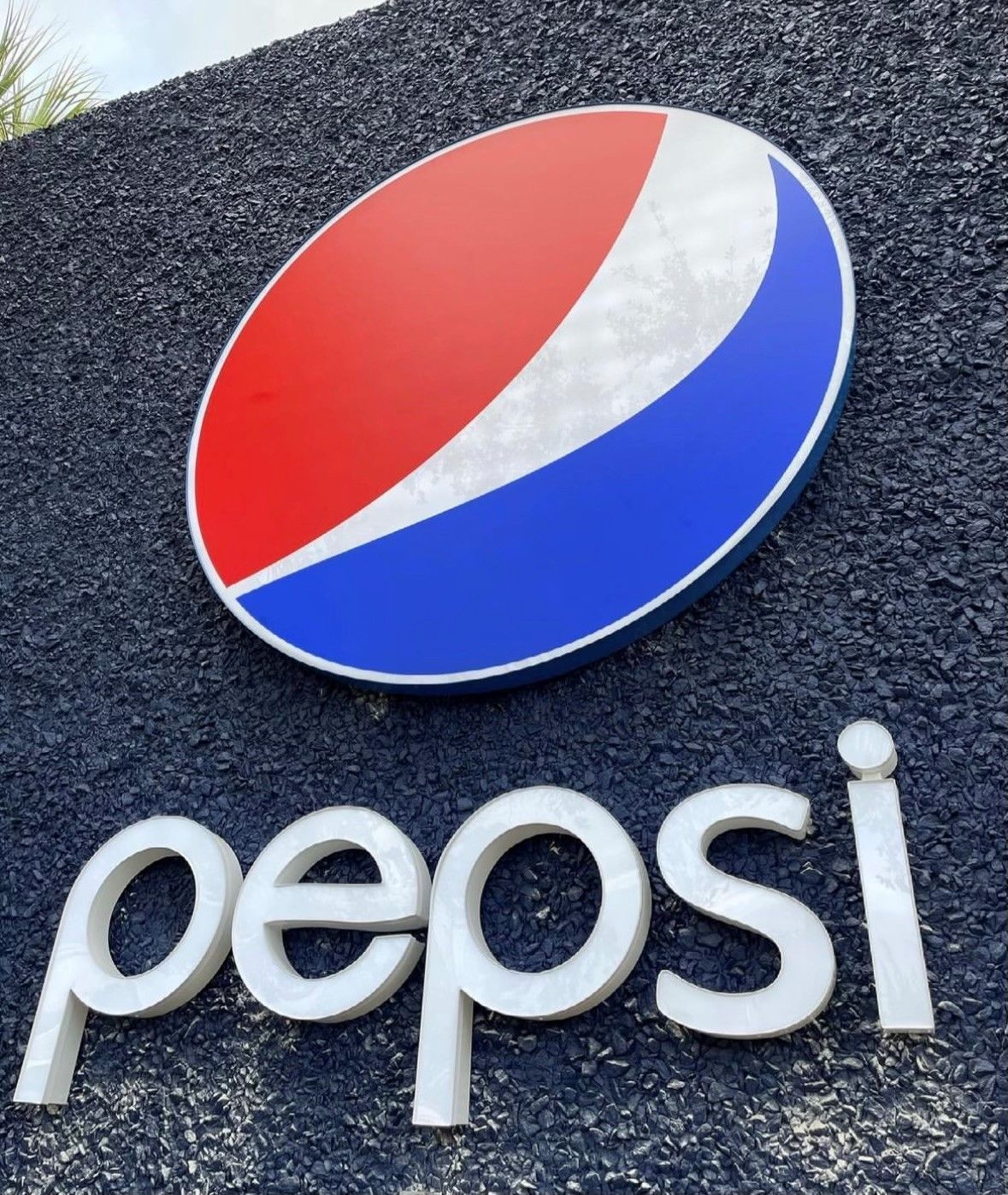 A pepsi sign that is outside on a gravel road