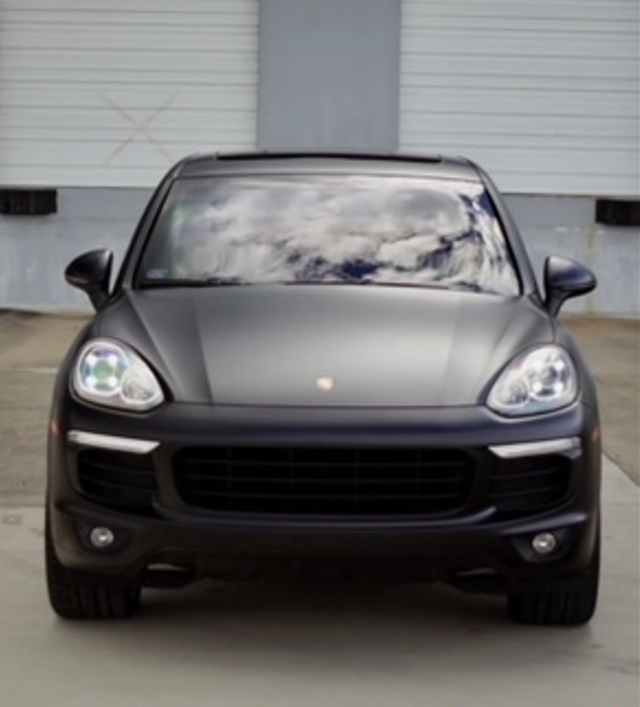 A black car is parked in front of a garage door