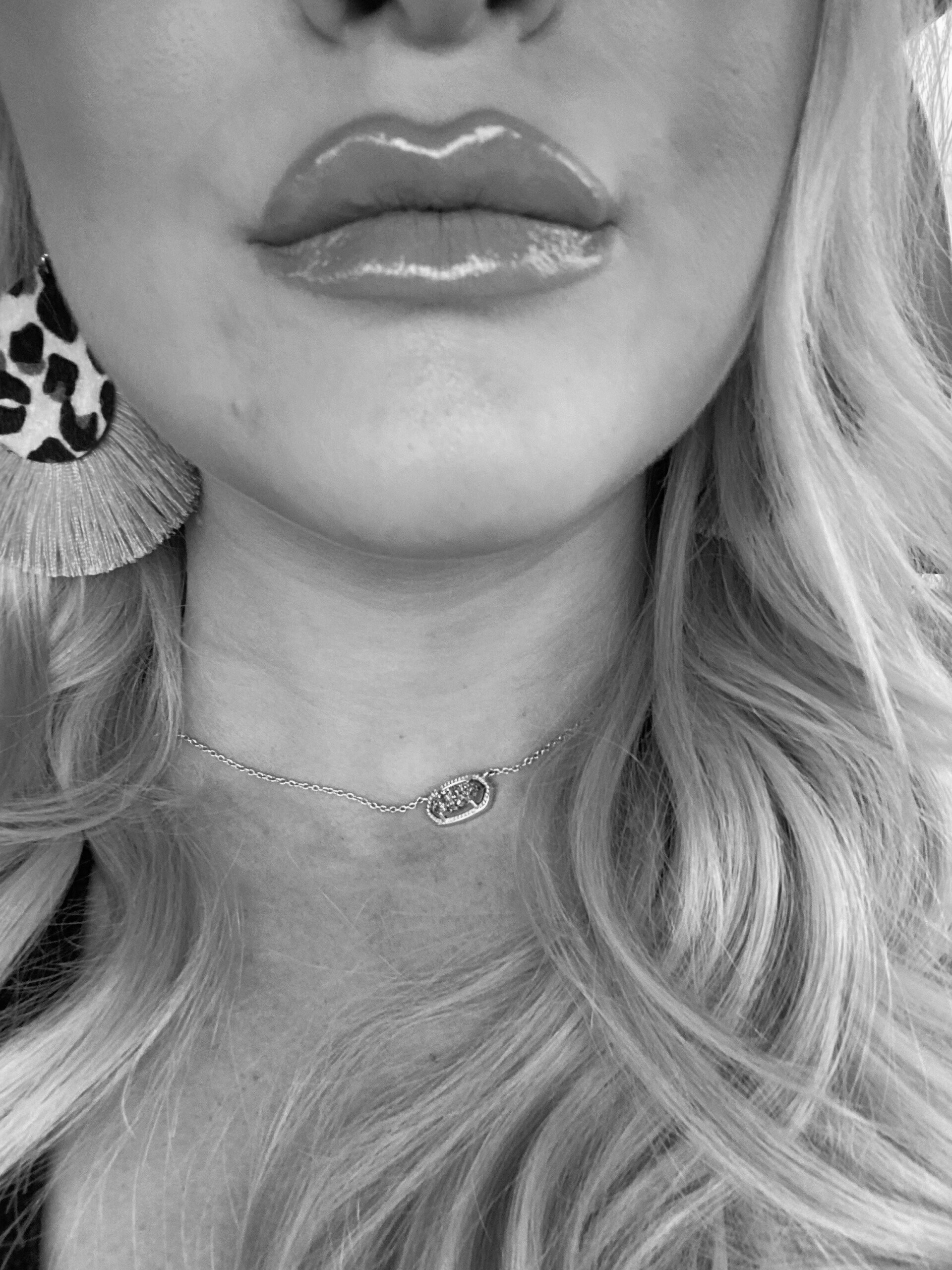 A black and white photo of a woman wearing a necklace and earrings.