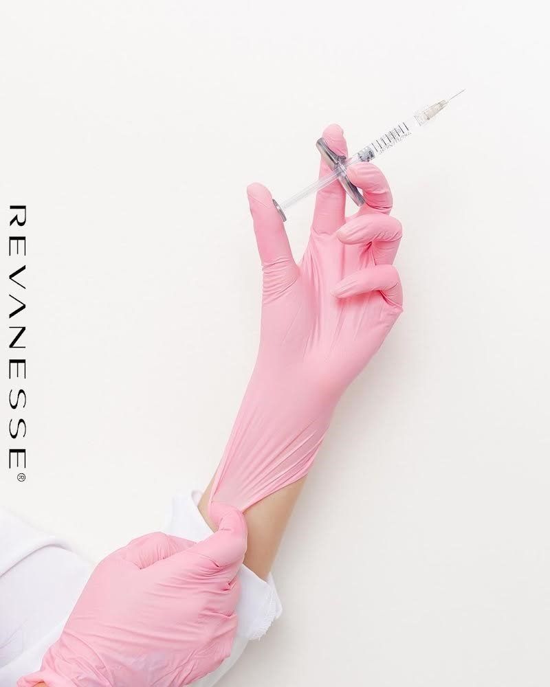 A person is putting on gloves and holding a syringe.