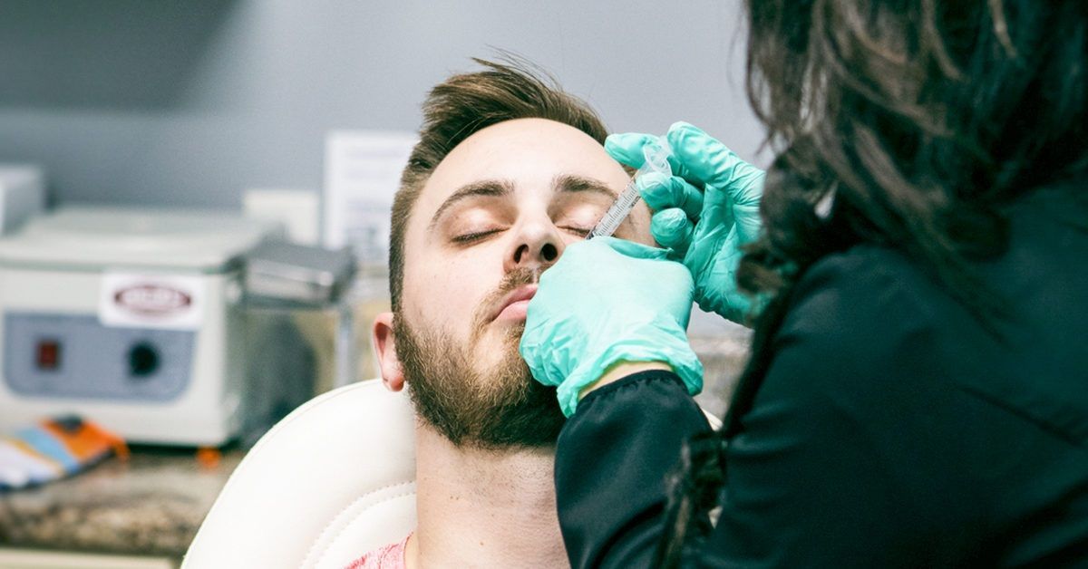 A man with a beard is getting a botox injection in his face.