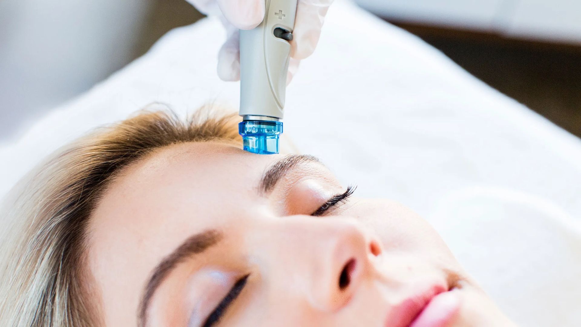 A woman is getting a facial treatment in a black and white photo.