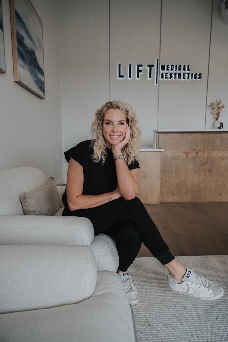 A woman is sitting on a couch in front of a sign that says lift medical aesthetics.