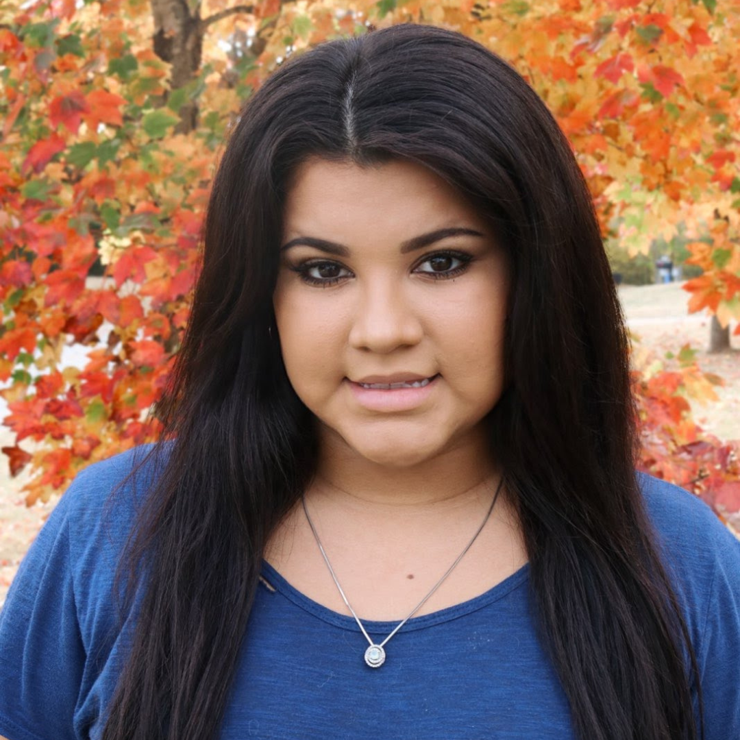 Blonde woman with a slight smile, wearing a grey sweatshirt, indoors.