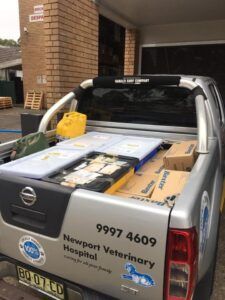 Silver Nissan truck bed loaded with supplies, parked outside Newport Veterinary Hospital.