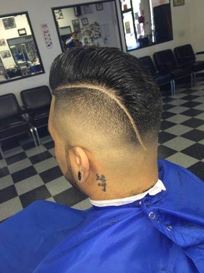 Man with a fade haircut and shaved side part in a barbershop.