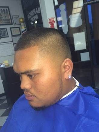 Man with a high fade haircut at a barbershop, wearing a blue cape.