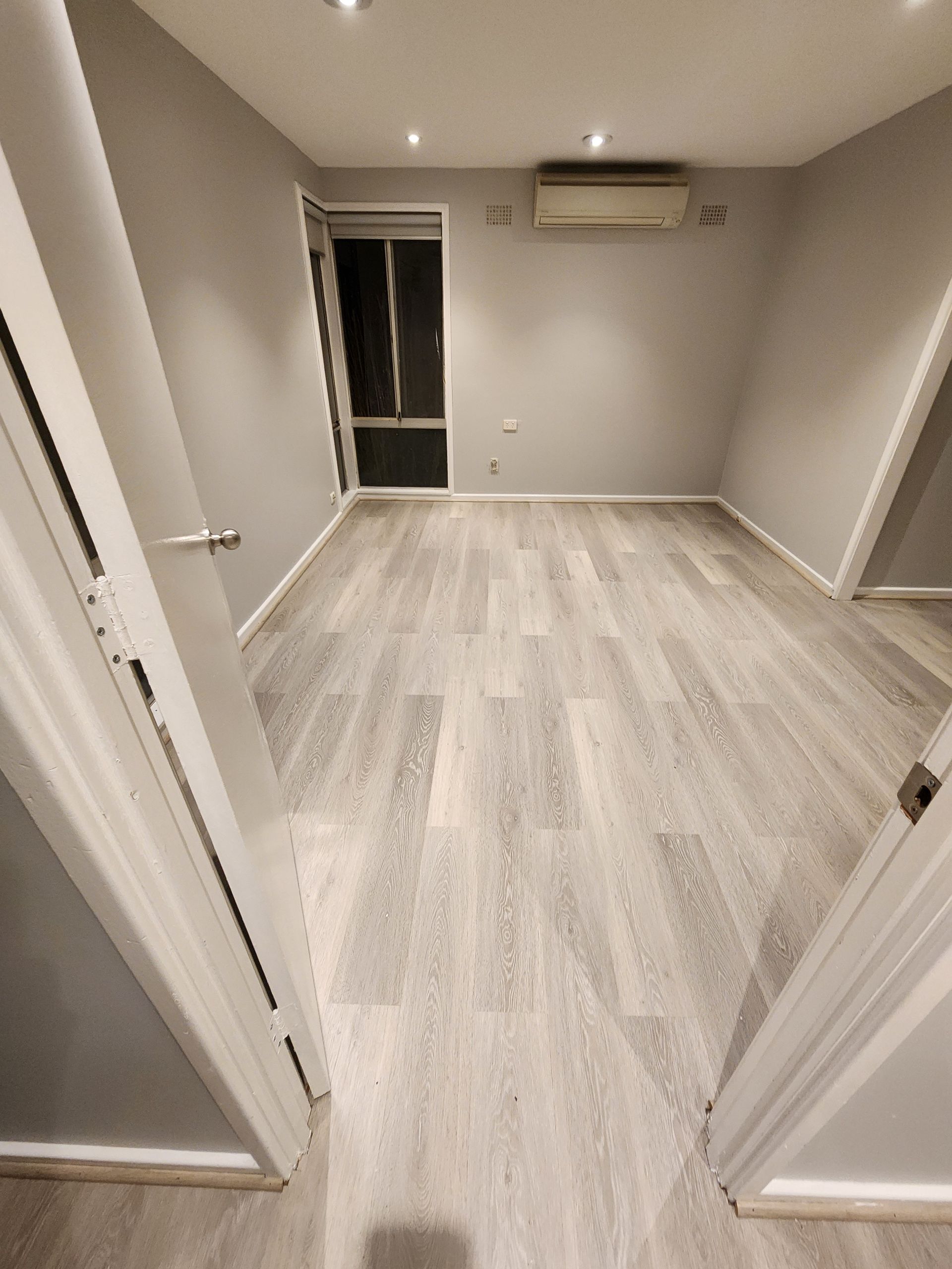 An empty room with hardwood floors and gray walls — Nicho's Home Maintenance In Tamworth, NSW