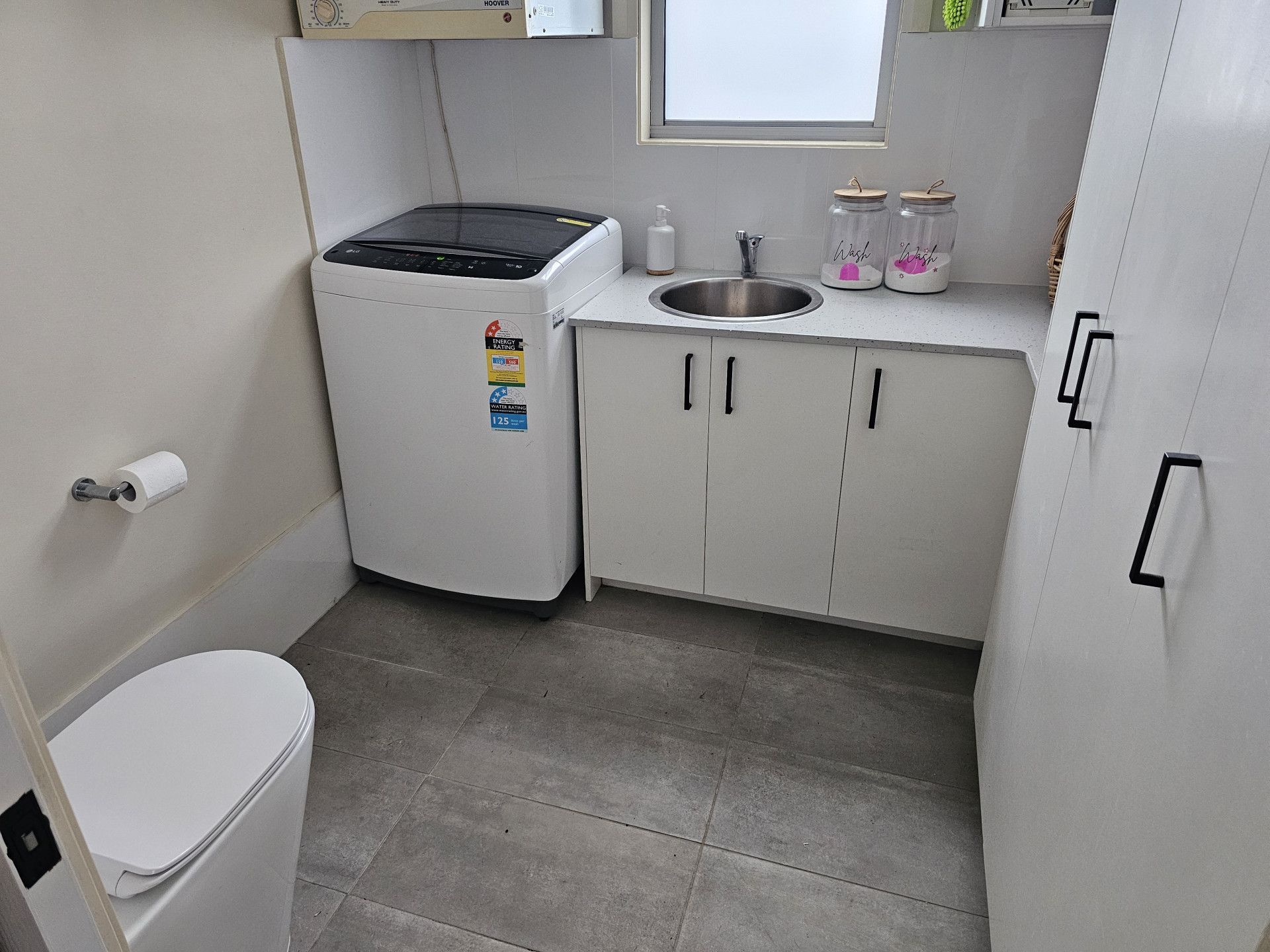 A bathroom with a toilet, sink, washer and dryer. — Nicho's Home Maintenance In Tamworth, NSW