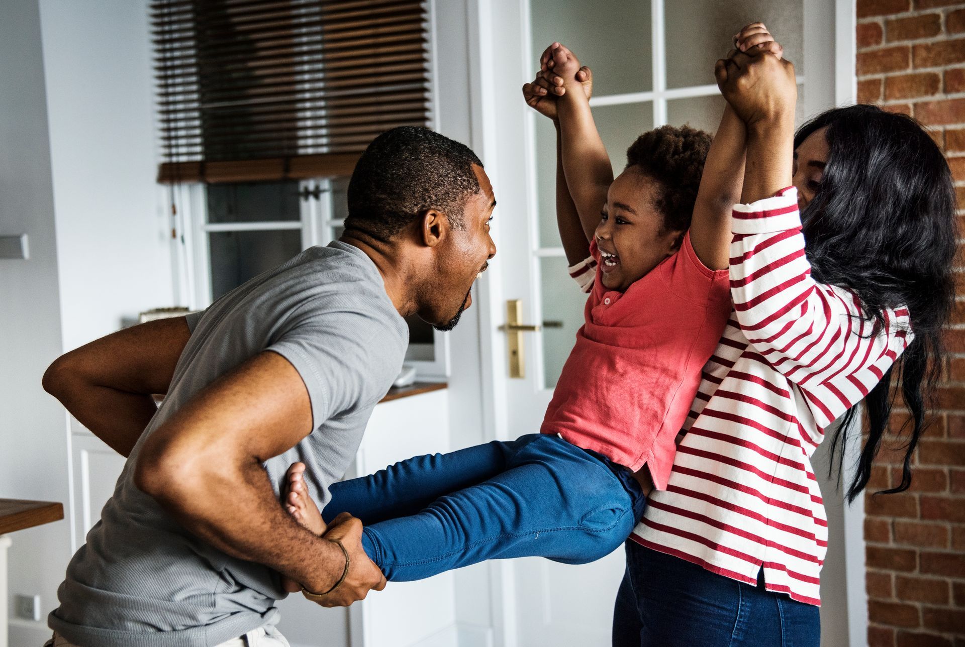 Family playing; parents hold child up in the air.