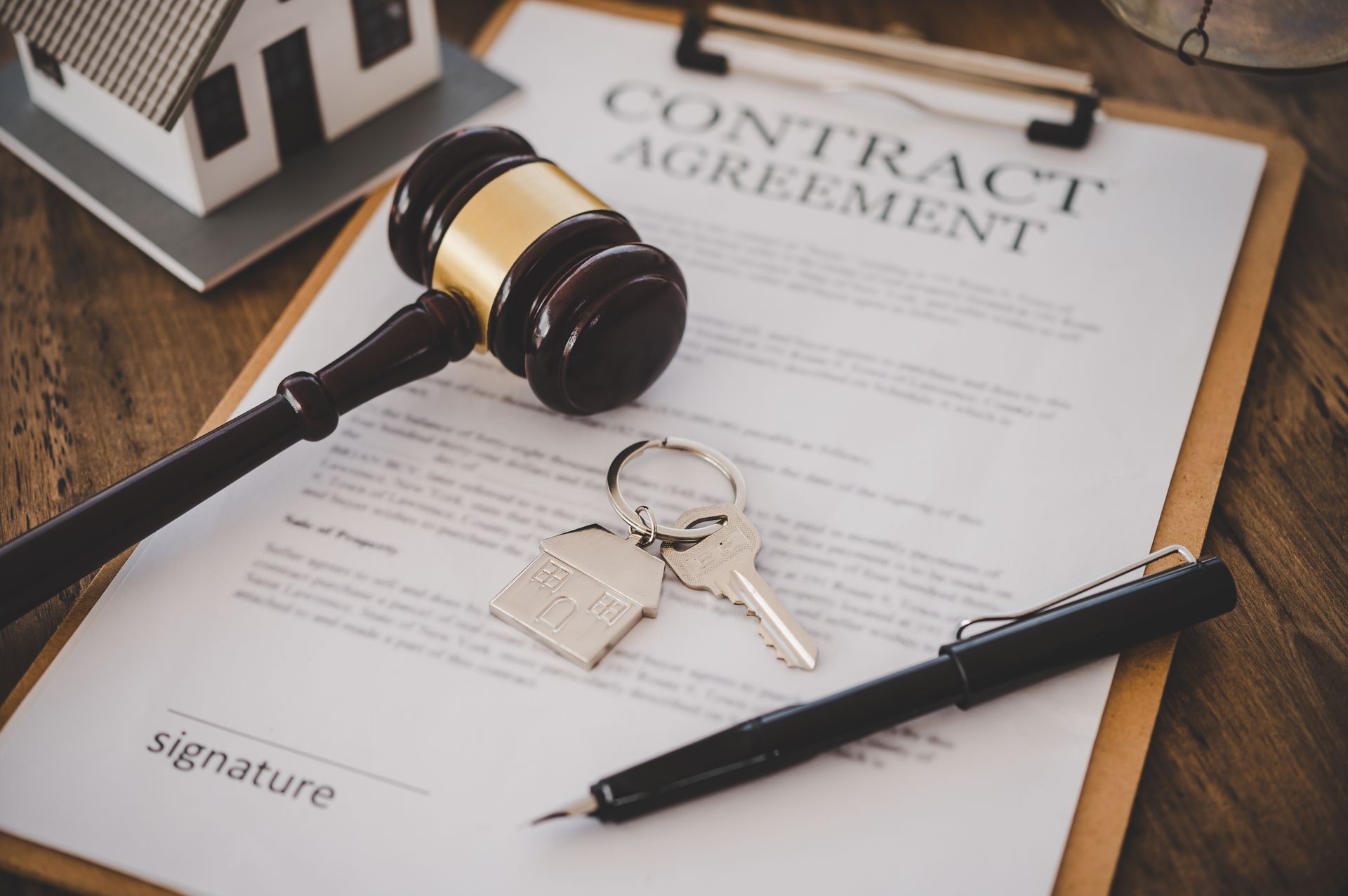 Gavel, keys, pen, and house model on a